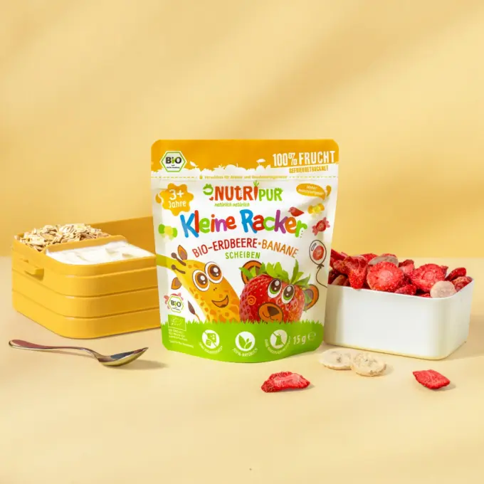 Billedet viser den økologiske “Lille Spilopmager” med jordbær-banan, fra NutriPur med yoghurt og flager som skolemad i en madkasse.