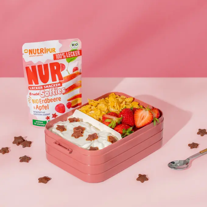 Billedet viser det økologiske bløde frugtslik “Softies” med jordbær og æble, som skolesnack i en madkasse.