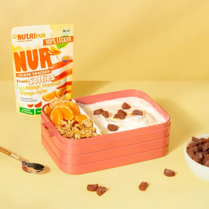 Billedet viser det økologiske bløde frugtslik “Softies” med mango, passionsfrugt, appelsin og æble som en madpakke-snack i en madkasse.